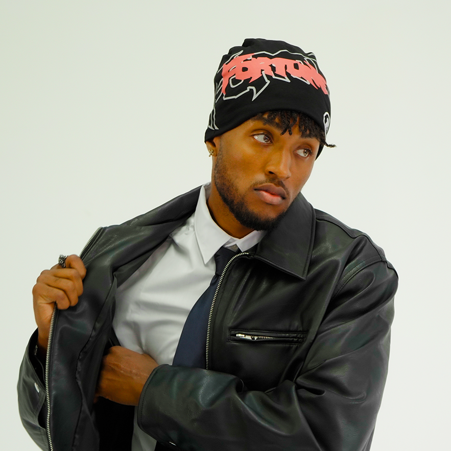 Person wearing a black leather jacket and a black beanie with red text on a white background